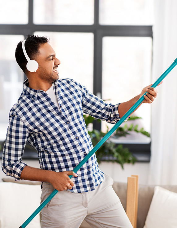 Man in Kopfhörer mit Besen als Luftgitarre